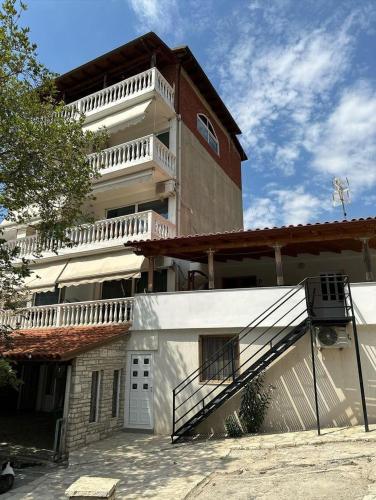 a large building with a staircase in front of it at Polyxeni Apartments & Rooms in Qeparo