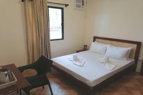a bedroom with a bed with two cups and a chair at Avila's Hostel Moalboal near Beach in Basdiot