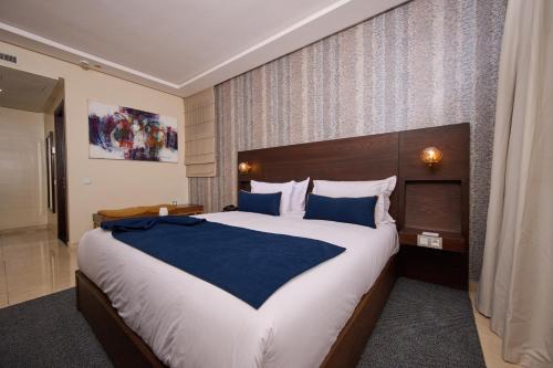 a bedroom with a large bed with blue pillows at Fourteen Hotel Ain Sebaa in Casablanca