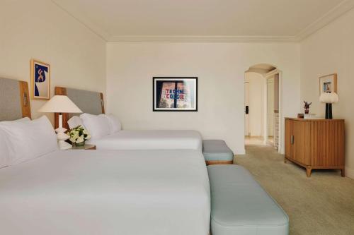 a hotel room with two beds and a couch at The Maybourne Beverly Hills, Maybourne in Los Angeles