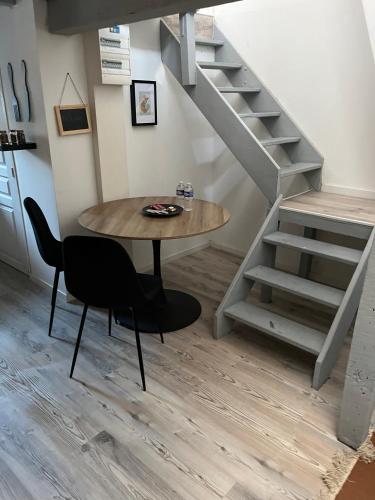 a table and chairs in a room with a staircase at Appartements Avesnes sur Helpe Centre ville T2 in Avesnes-sur-Helpe