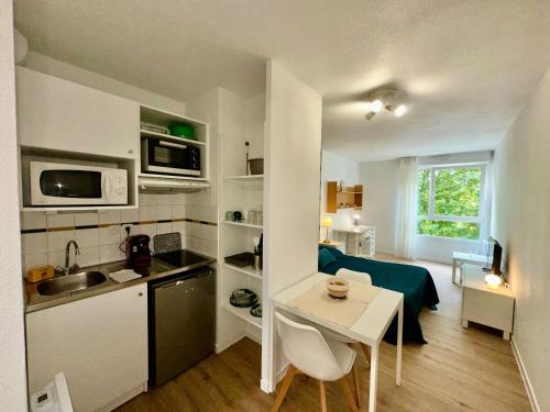 a small kitchen and living room with a table in a room at Sphinx Résidences - Tempologis Mémorial in Caen
