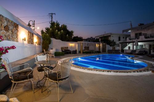 a patio with a table and chairs and a swimming pool at Toula's Apartments in Faliraki