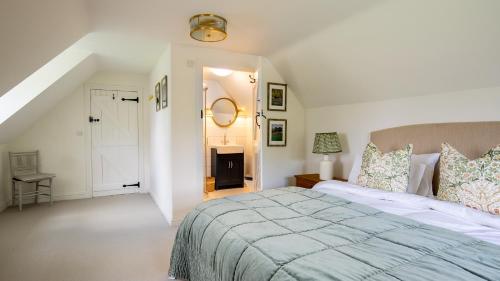 a white bedroom with a large bed and a staircase at Patch Hill House in Finstock