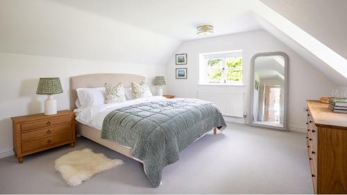 a white bedroom with a bed and a window at Patch Hill House in Finstock