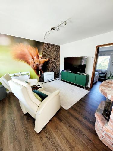 a living room with a white couch and a tv at Ferienhaus Grüner Bungalow Kontaktloser CheckIn in Stendell