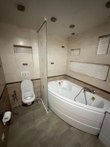 een badkamer met een wit bad en een toilet bij 2 ком люкс в центре города in Karagandy