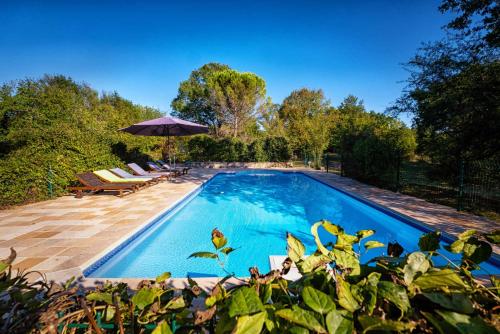 une piscine avec des chaises et un parasol dans l'établissement La Maison des Chênes - Piscine et grand terrain arboré dans une ambiance bucolique., à Cahuzac-sur-Vère