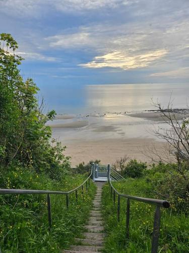 un escalier menant à une plage donnant sur l'océan. dans l'établissement La Maison des Saveurs, à Trouville-sur-Mer