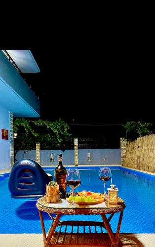 a table with two wine glasses next to a swimming pool at Vila Darli Peshkopi Dibra in Peshkopi