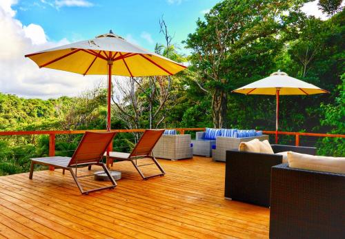 a deck with two chairs and two umbrellas at Blue Whale Villa - Penthouse in Calibishie