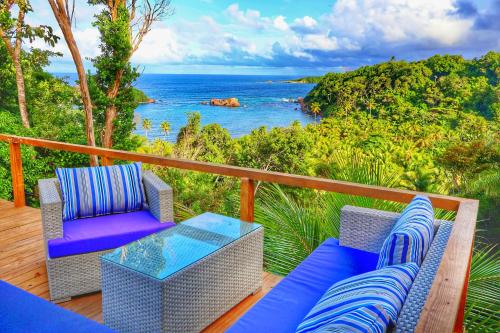 a balcony with two chairs and a table and the ocean at Blue Whale Villa - Penthouse in Calibishie