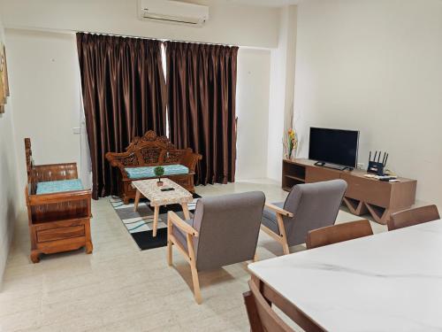 a living room with a table and chairs and a television at By The Sea Beach Front Sea view Apartment 3 in Batu Ferringhi