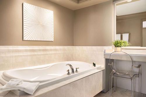 a bathroom with a bath tub and a window at Ramada by Wyndham Cornwall in Cornwall