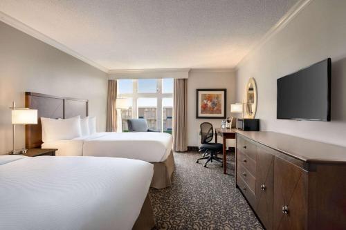a hotel room with two beds and a desk at Ramada by Wyndham Cornwall in Cornwall