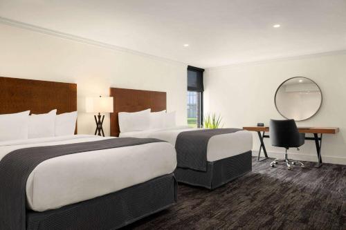 a hotel room with two beds and a mirror at Ramada by Wyndham Cornwall in Cornwall