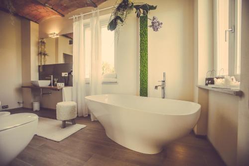 a bathroom with a large white tub and a window at Langhe Country House in Neive