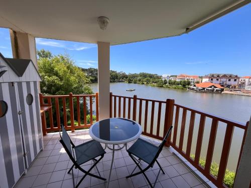 a table and chairs on a balcony with a view of a river at l'orée du lac in Talmont