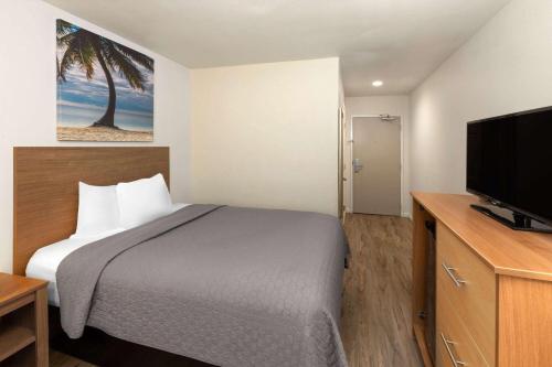 a hotel room with a bed and a flat screen tv at Days Inn by Wyndham Biloxi Beach in Biloxi