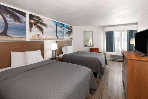 a hotel room with two beds and a flat screen tv at Days Inn by Wyndham Biloxi Beach in Biloxi