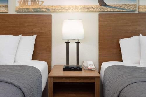 a hotel room with two beds and a phone on a table at Days Inn by Wyndham Biloxi Beach in Biloxi