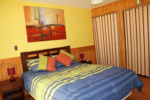 a bedroom with a blue bed with colorful pillows at Cabañas Bordenieve in Las Trancas