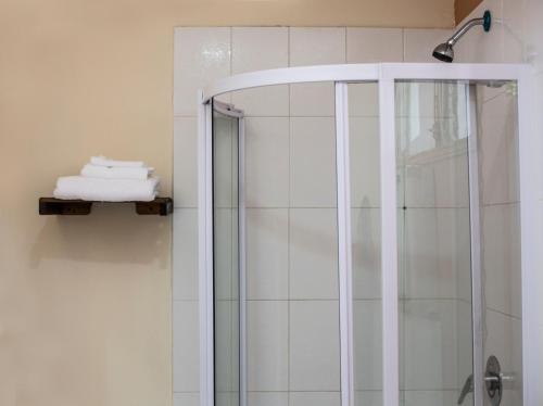 una ducha con puerta de cristal y toallas en un estante en La Bellota Hotel en Siguatepeque