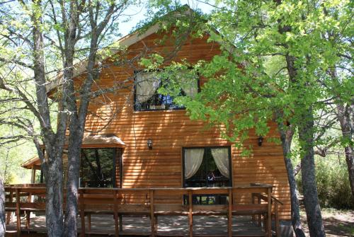 a log cabin in the woods with a table and benches at Cabañas Bordenieve in Las Trancas