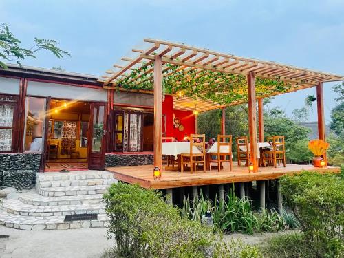 a house with a wooden deck with tables and chairs at Wild Tracks Overland Camp in Kasese