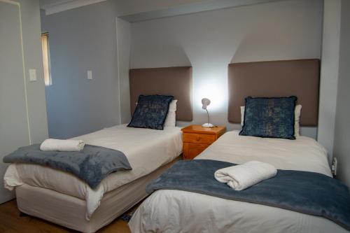 a bedroom with two beds with blue pillows at Great White Accommodation in Kleinbaai