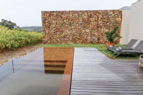a garden with a wooden floor and a stone wall at Monverde - Wine Experience Hotel - by Unlock Hotels in Amarante