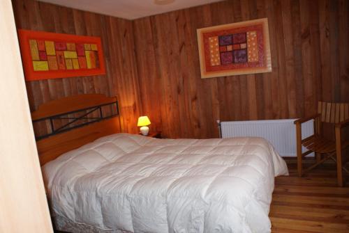 a bedroom with a white bed and wooden walls at Cabañas Bordenieve in Las Trancas