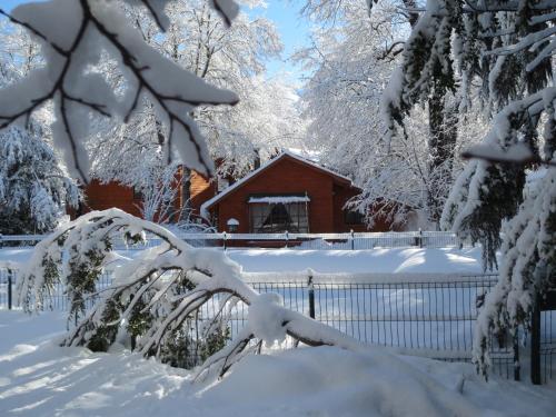 a house covered in snow in front of a fence at Cabañas Bordenieve in Las Trancas