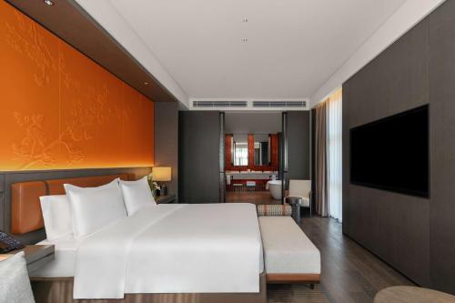 a bedroom with a large white bed and a television at Doubletree By Hilton Kaifeng in Kaifeng