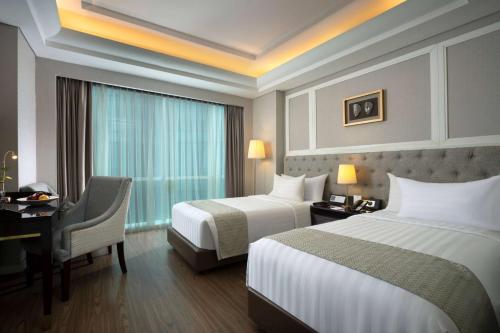 a hotel room with two beds and a desk at Wyndham Panbil Batam in Batam Center