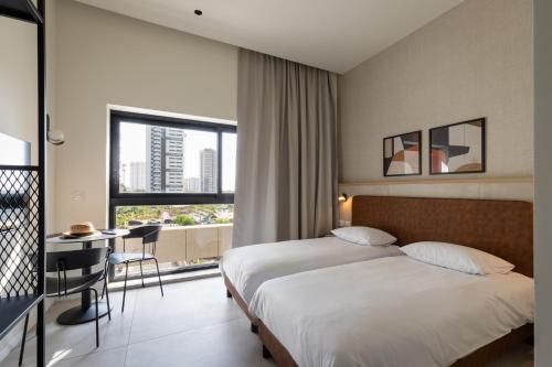 a hotel room with a bed and a desk and a window at Tayo Studios & Apartments in Bat Yam