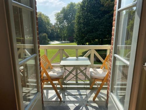 a porch with two chairs and a table and a table at La Maison du Cavalier, Chateau de lAvenue in Pierrefitte-en-Auge