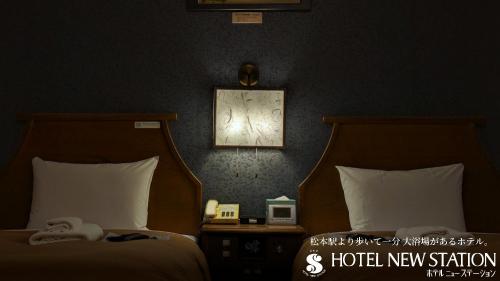 a bedroom with two beds and a picture on the wall at Hotel New Station in Matsumoto