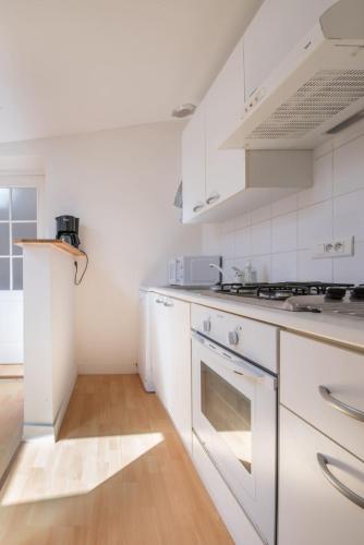 Il comprend une cuisine blanche avec des appareils électroménagers blancs et du parquet. dans l'établissement Maison mitoyenne- 4 pers - Centre historique de Pornic, à Pornic