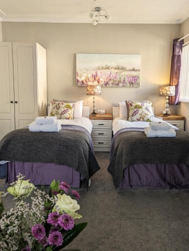 a bedroom with two beds and flowers in it at Alexander Lodge in Bournemouth