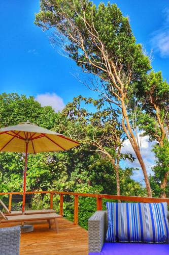 a wooden deck with a table and an umbrella at Blue Whale Villa - Deluxe in Calibishie
