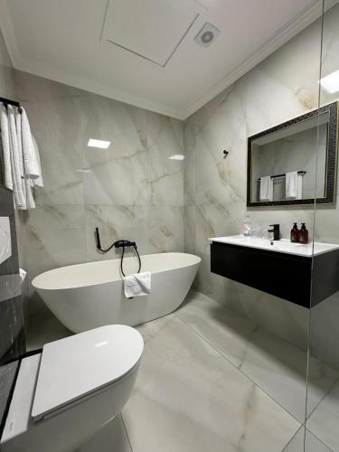 a bathroom with a tub and a toilet and a sink at Palm House Boutique Hotel and Spa in Cape Town