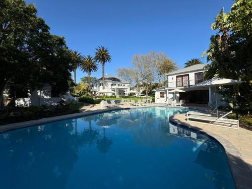 a large blue swimming pool in front of a house at Palm House Boutique Hotel and Spa in Cape Town