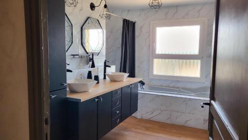 La salle de bains est pourvue de 2 lavabos, d'une baignoire et d'une fenêtre. dans l'établissement La Villa Ganesh : maison de campagne dans le Gard !, à Saint-André-dʼOlérargues