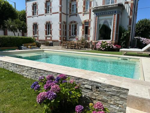 - une piscine en face d'une maison fleurie dans l'établissement Villa Gabrielle De La Mer avec Piscine Privée, à Étables
