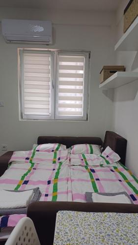 a bed sitting in a room with two windows at Studio Mili in Malovići
