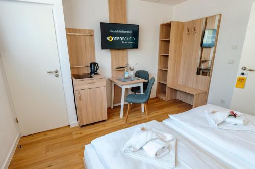 a room with two beds and a table and a desk at Sonnenschein Hotel & Apartments in Heilbad Heiligenstadt