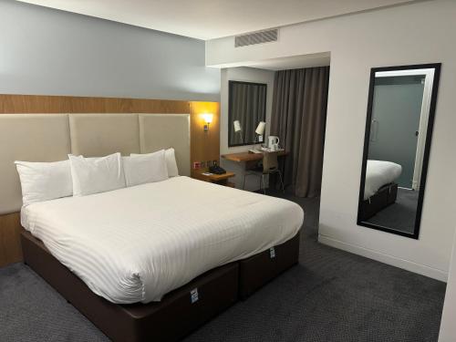 a hotel room with a large bed and a mirror at Holiday Inn Sittingbourne by IHG in Sittingbourne