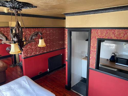 a room with a red wall with a door and a fireplace at Keats Green Hotel in Shanklin