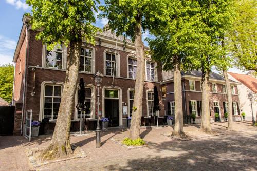 a brick building with trees in front of it at Appartement Nu in Eersel